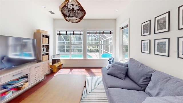 living room featuring visible vents, dark wood-type flooring, baseboards, and a sunroom