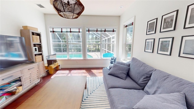 living room featuring dark wood finished floors, visible vents, baseboards, and a sunroom