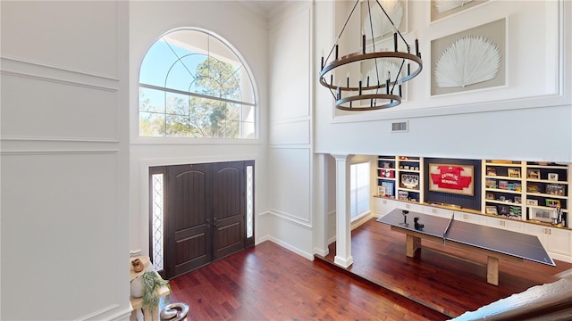 entrance foyer with wood finished floors, visible vents, and ornate columns