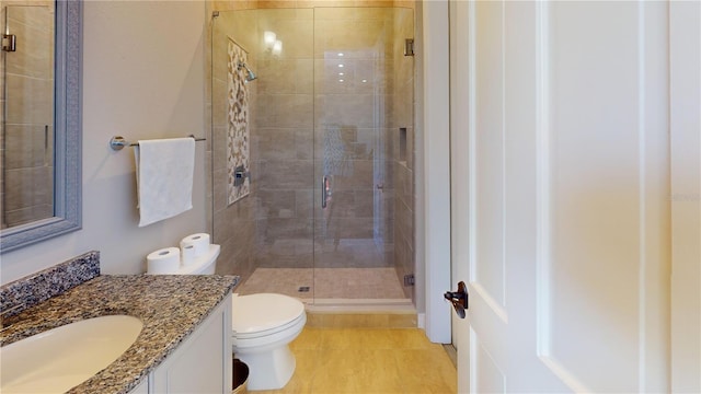 full bathroom with vanity, a shower stall, and toilet