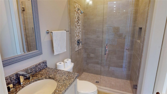 full bath with a stall shower, toilet, and vanity