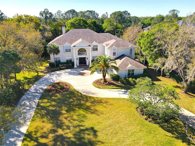 view of front of house featuring stucco siding, driveway, and a front lawn