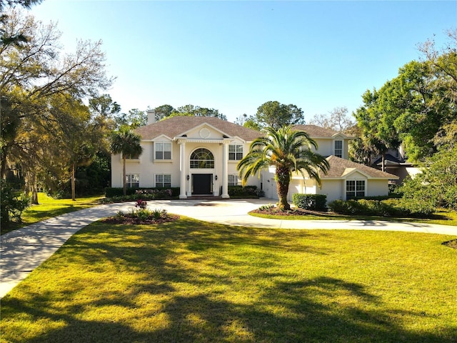 view of front of house featuring a front lawn, stucco siding, and curved driveway