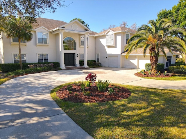 view of front of house with stucco siding, a front lawn, curved driveway, and an attached garage