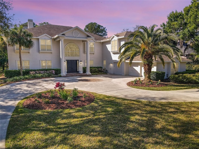 view of front facade with a lawn, concrete driveway, and stucco siding