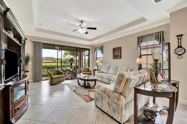 living room featuring ceiling fan, a tray ceiling, baseboards, and light tile patterned flooring