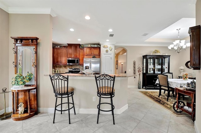 kitchen featuring arched walkways, appliances with stainless steel finishes, crown molding, and a kitchen breakfast bar