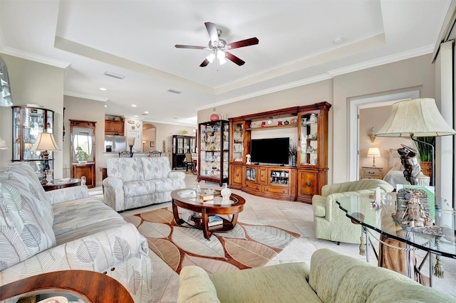 living area featuring a tray ceiling, light tile patterned floors, crown molding, and visible vents