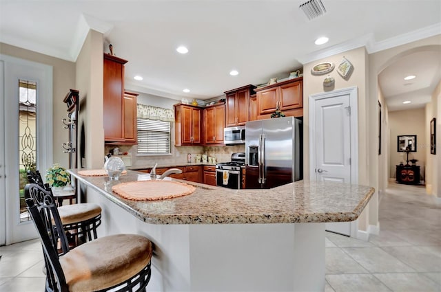 kitchen with a breakfast bar, a sink, decorative backsplash, appliances with stainless steel finishes, and crown molding