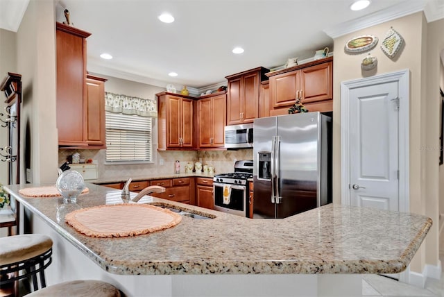 kitchen with backsplash, light stone countertops, appliances with stainless steel finishes, a kitchen breakfast bar, and a sink
