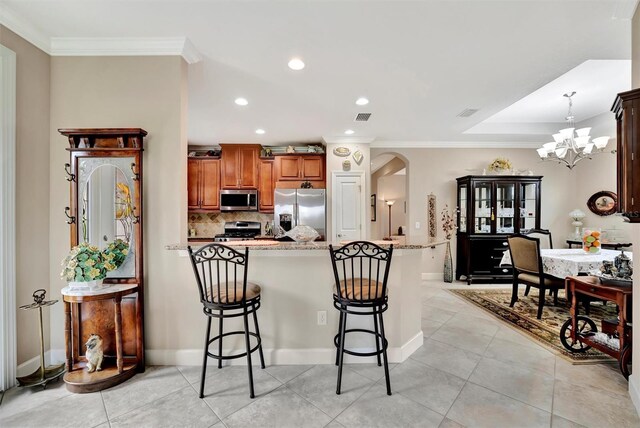kitchen featuring stainless steel appliances, arched walkways, a breakfast bar area, and crown molding