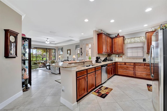 kitchen with light tile patterned flooring, stainless steel appliances, a tray ceiling, and a sink