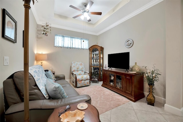 living area featuring baseboards, a tray ceiling, ornamental molding, light tile patterned floors, and a ceiling fan