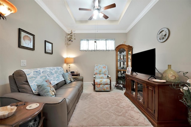 living area featuring a raised ceiling, light carpet, a ceiling fan, and crown molding