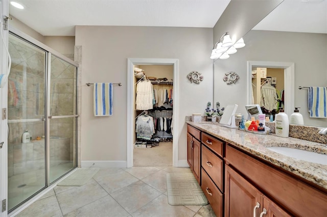 full bathroom with a walk in closet, a stall shower, a sink, tile patterned flooring, and double vanity