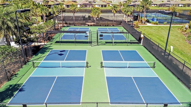 view of tennis court with a residential view and fence