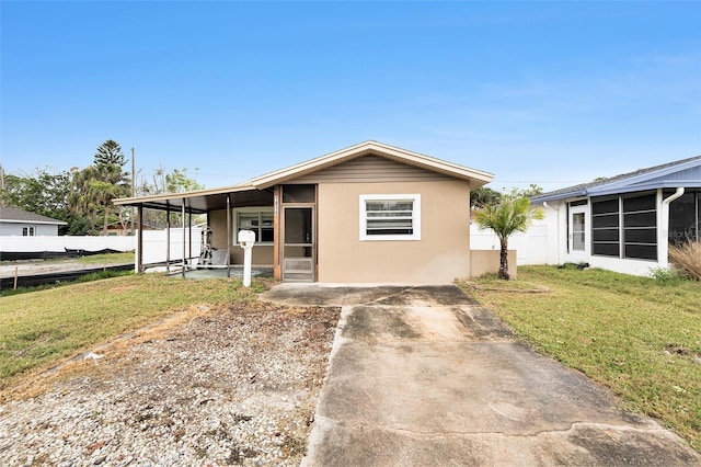 view of front of property featuring stucco siding, a sunroom, a front lawn, and fence