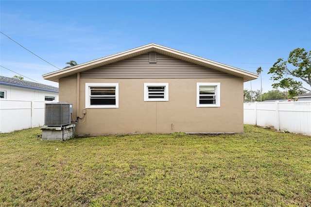 back of house with fence, a lawn, central AC, and stucco siding