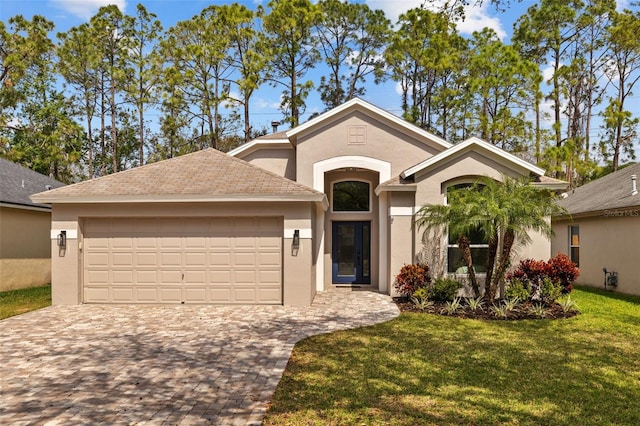 view of front of house with decorative driveway, a front yard, an attached garage, and stucco siding