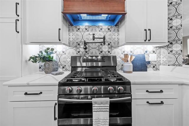 kitchen with tasteful backsplash, white cabinetry, light stone countertops, custom exhaust hood, and stainless steel gas range