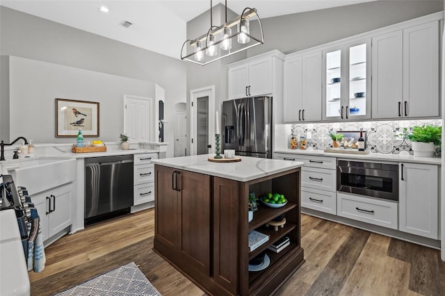 kitchen with dark wood finished floors, stainless steel appliances, glass insert cabinets, and a sink