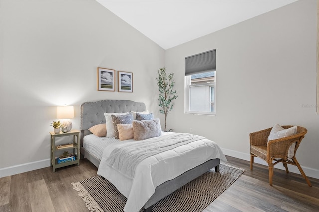 bedroom with lofted ceiling, wood finished floors, and baseboards