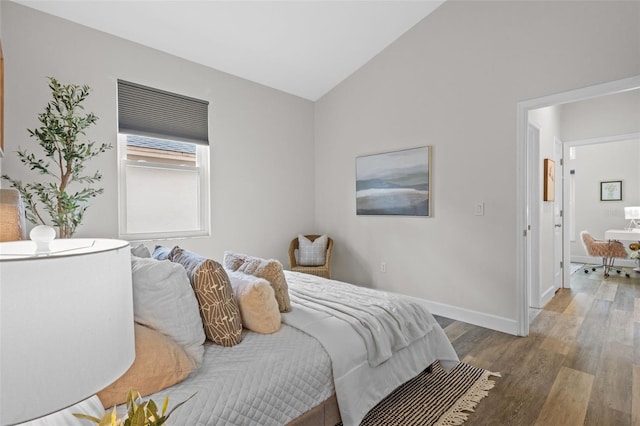 bedroom featuring baseboards, lofted ceiling, and wood finished floors