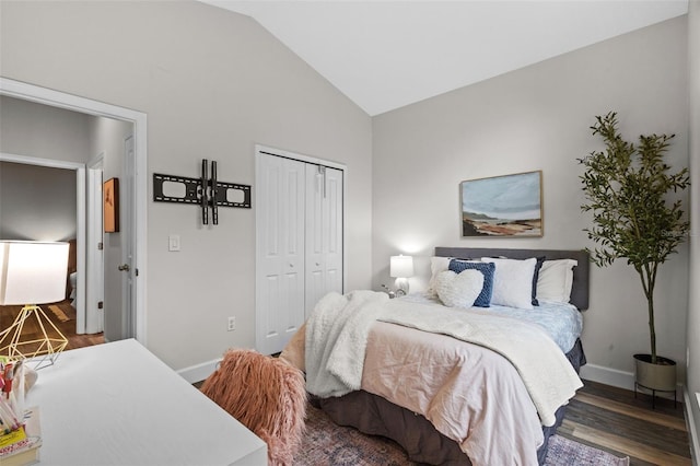 bedroom with a closet, wood finished floors, baseboards, and vaulted ceiling