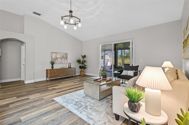 living room featuring visible vents, wood finished floors, an inviting chandelier, baseboards, and vaulted ceiling