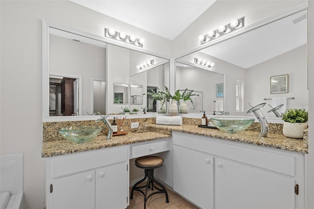 bathroom featuring vaulted ceiling, visible vents, tile patterned floors, and a sink