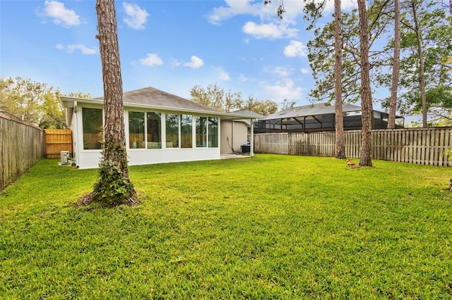 rear view of property with cooling unit, a lawn, a fenced backyard, and a sunroom