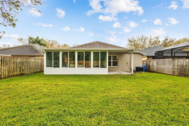 rear view of property with a yard, central air condition unit, a fenced backyard, and a sunroom