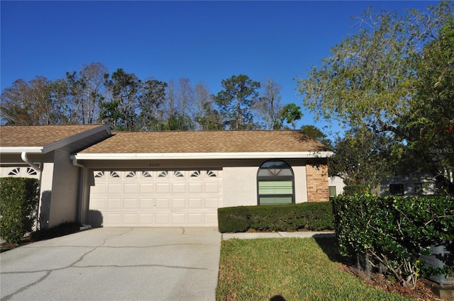 view of front facade with a shingled roof, concrete driveway, an attached garage, and stucco siding