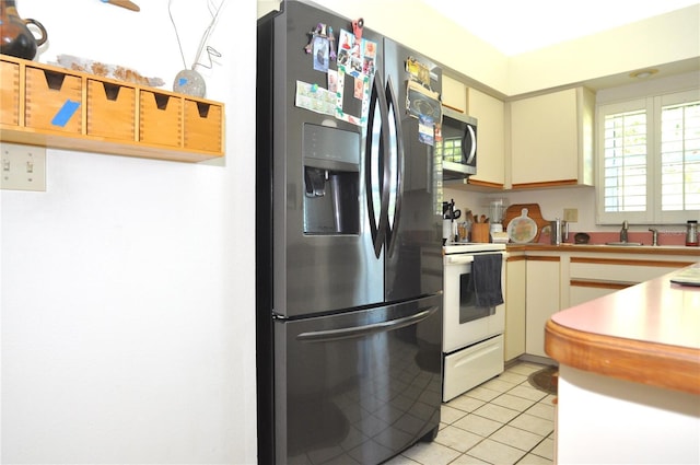 kitchen with light tile patterned floors, appliances with stainless steel finishes, and a sink