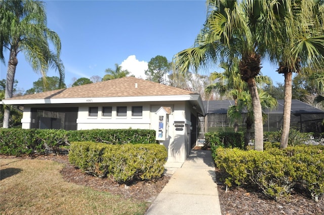 view of front of home with a shingled roof, a lanai, and stucco siding