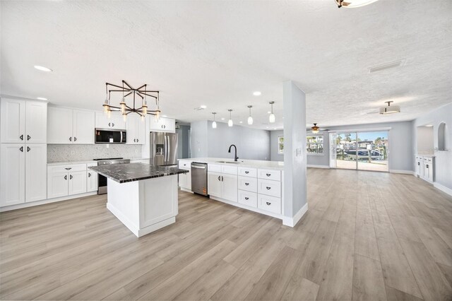 6410 3rd Palm Pt, St Pete Beach, FL 33706 - kitchen featuring light wood finished floors, a sink, open floor plan, a kitchen island, and appliances with stainless steel finishes