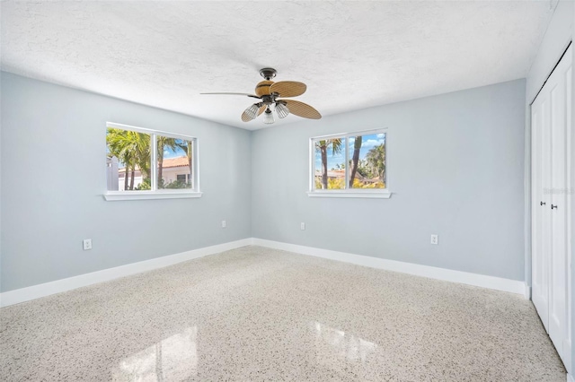 6410 3rd Palm Pt, St Pete Beach, FL 33706 - unfurnished bedroom with speckled floor, a ceiling fan, a closet, baseboards, and a textured ceiling