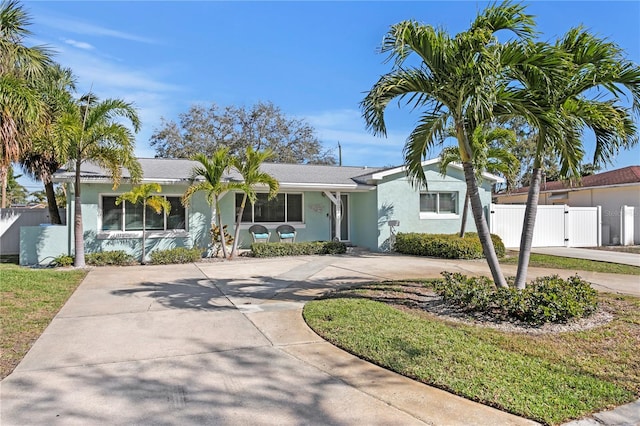 ranch-style home with a gate, stucco siding, driveway, and fence