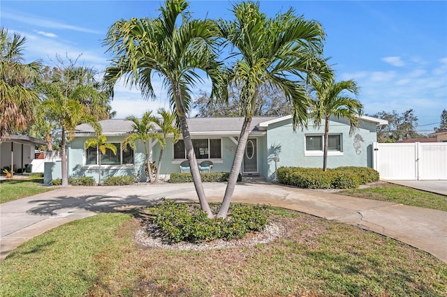 view of front of property featuring stucco siding, driveway, a gate, fence, and a front yard