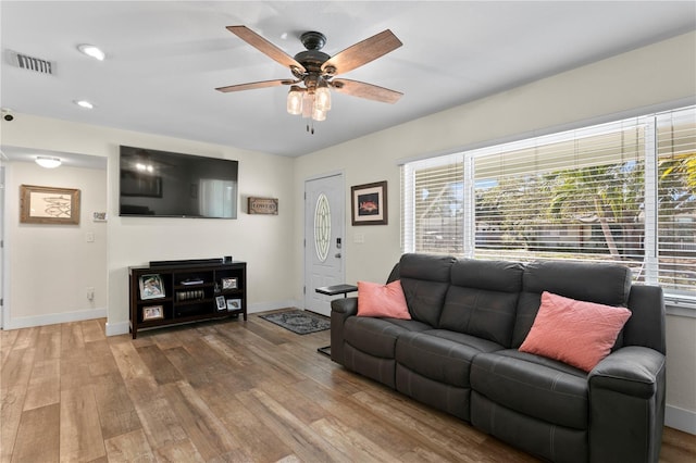 living room with baseboards, wood finished floors, visible vents, and a healthy amount of sunlight