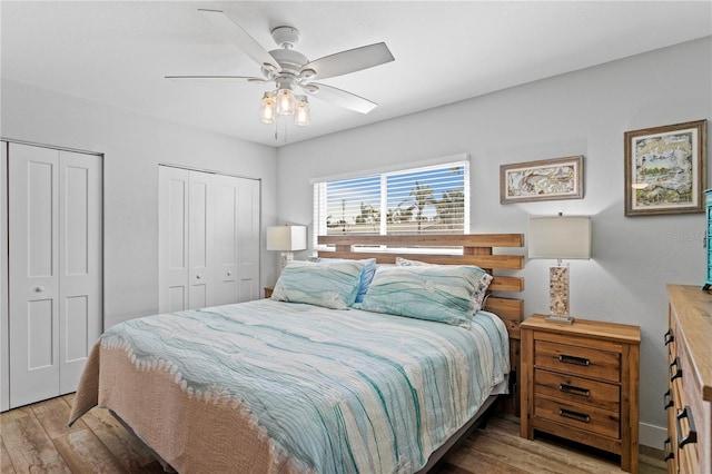 bedroom with ceiling fan, two closets, and wood finished floors