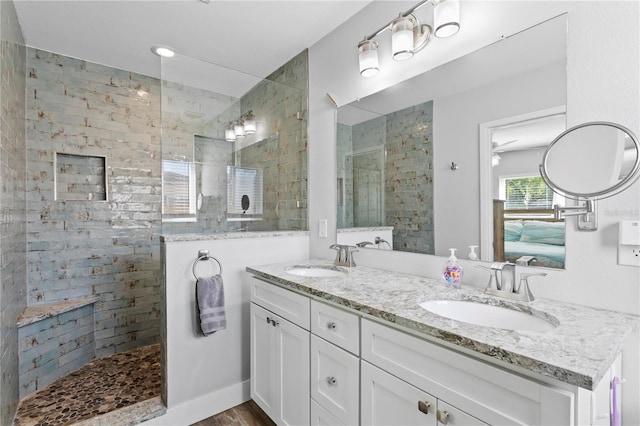 full bathroom featuring a sink, baseboards, double vanity, and a walk in shower