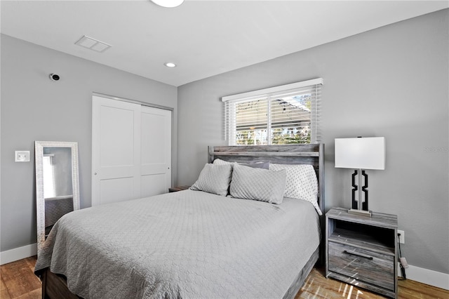 bedroom featuring a closet, visible vents, baseboards, and wood finished floors