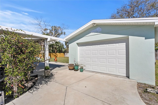 garage with concrete driveway and fence