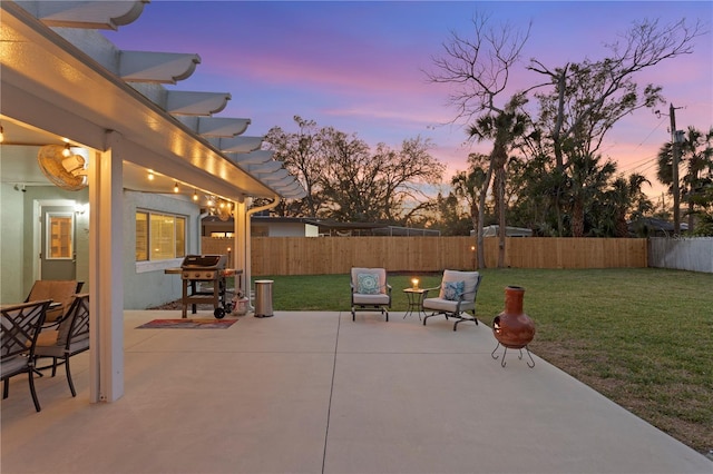 patio terrace at dusk featuring a yard, area for grilling, a fenced backyard, and a pergola