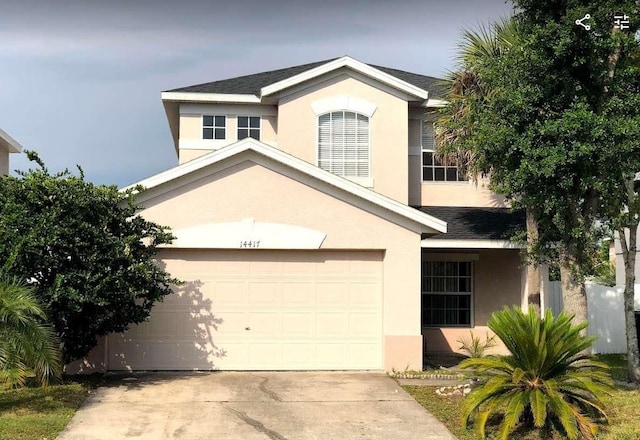 traditional-style home featuring stucco siding, an attached garage, and concrete driveway