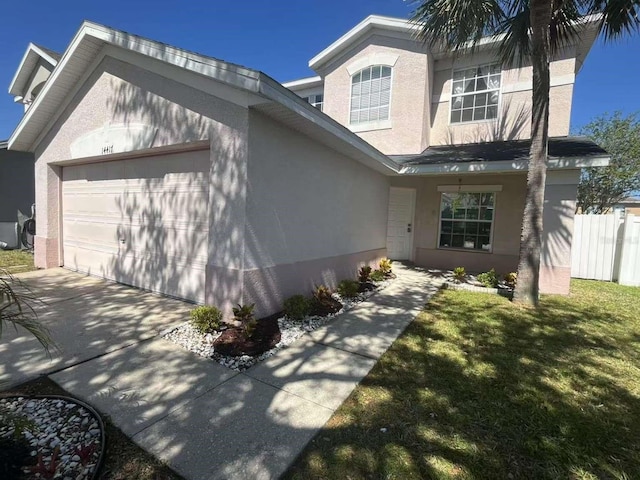 view of front of home featuring stucco siding, concrete driveway, a front lawn, and a garage