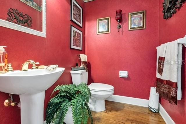 bathroom with baseboards, toilet, and wood finished floors