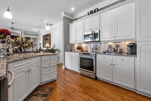 kitchen featuring a sink, wood finished floors, white cabinetry, stainless steel appliances, and dark stone counters