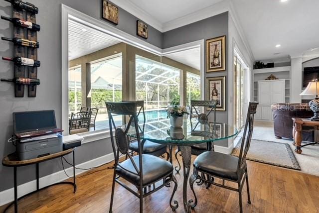 dining room with baseboards, wood finished floors, crown molding, and a sunroom